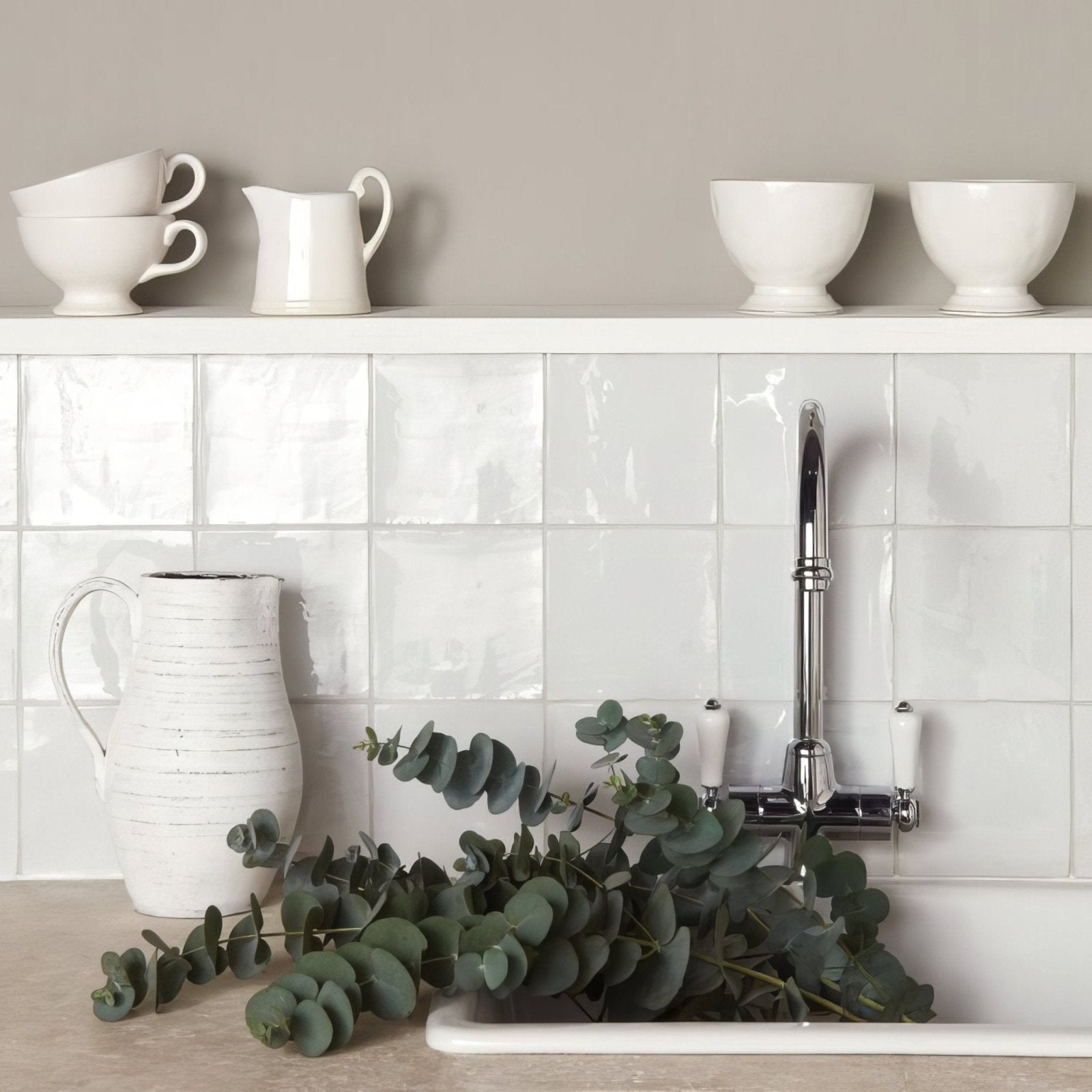 White ceramic pitcher with a textured handcrafted finish and curved handle on chalk field tile surface