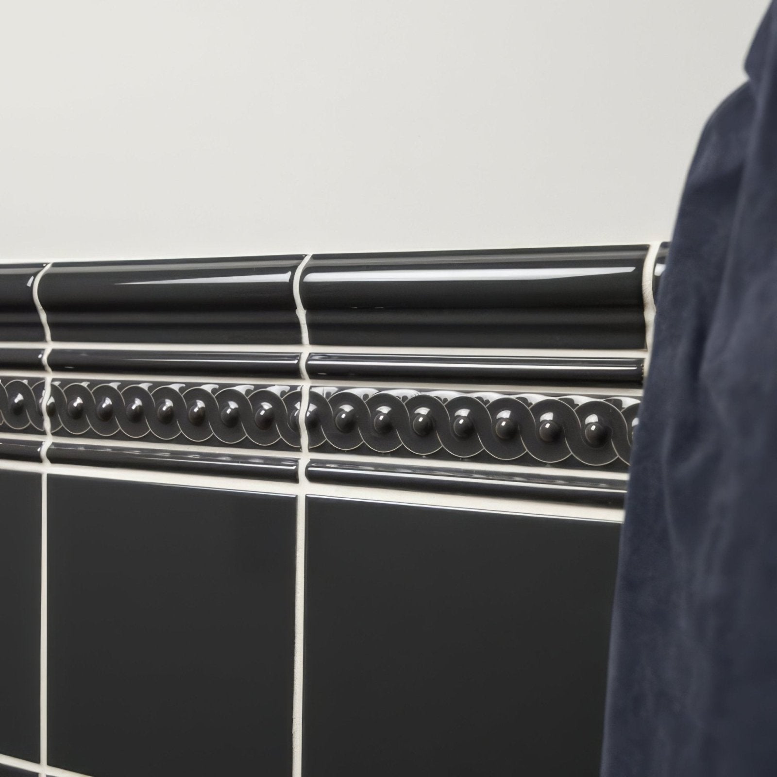 Black glossy ceramic tile border with decorative wavy bead pattern in charcoal grey omega moulding design