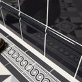 Charcoal Grey skirting tile in gloss ceramic finishing a hallway dado above a Victorian geometric floor, with white grout