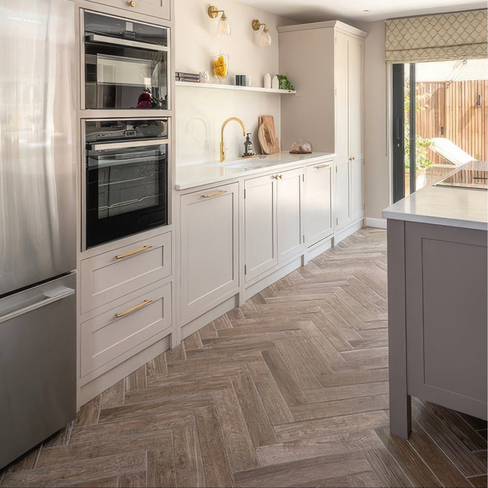 Modern white kitchen cabinets with gold toned handles and chatham porcelain oak herringbone wood look floor