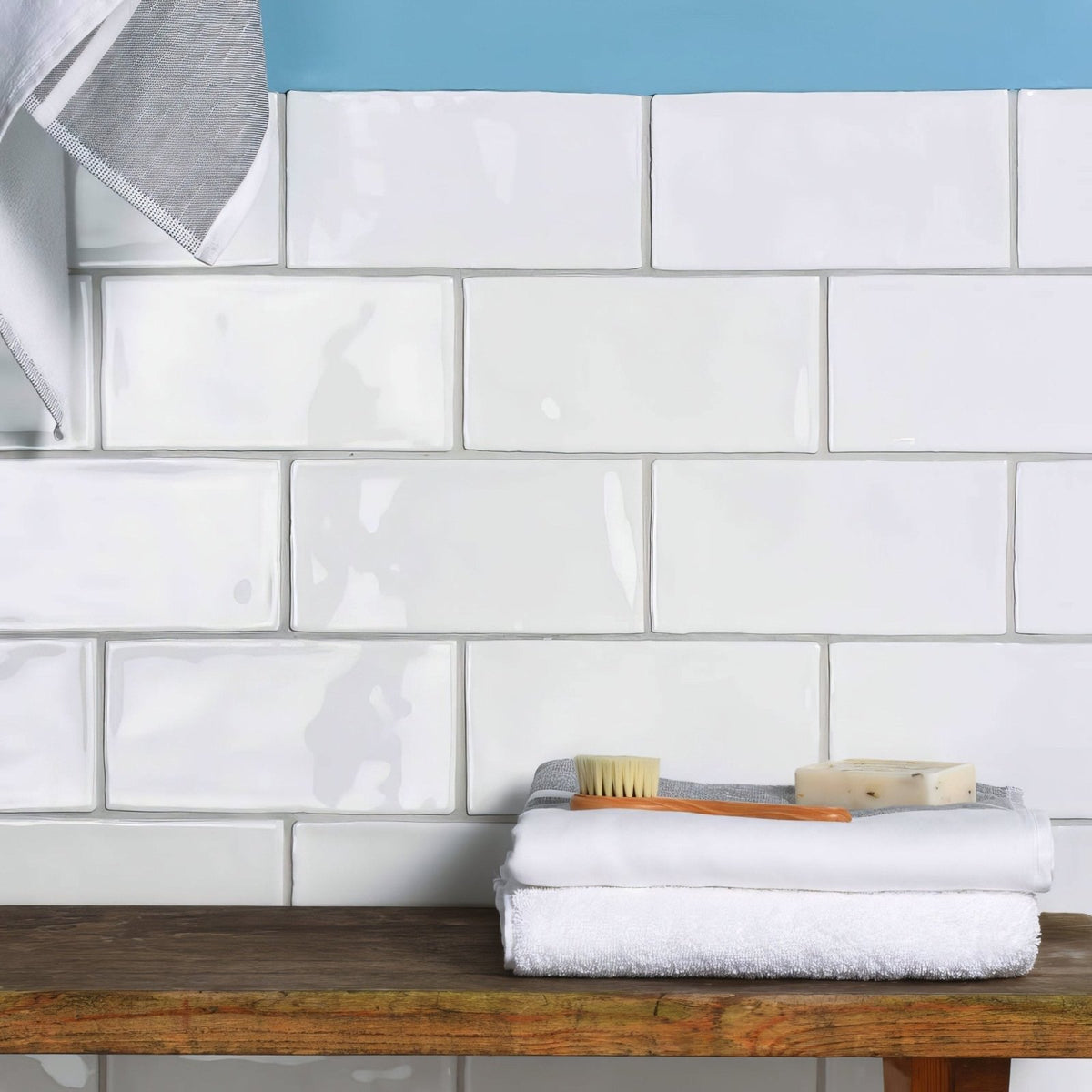 Stack of neatly folded white cotton towels on wooden surface complementing china white brick tile decor