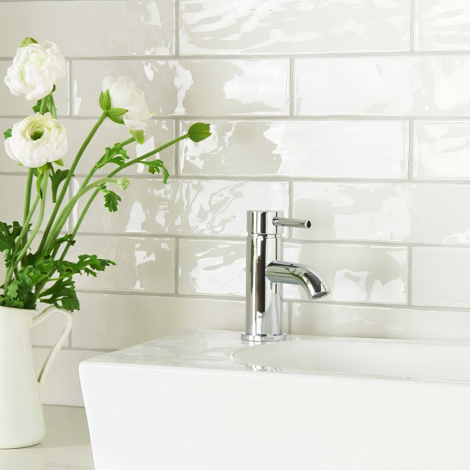 Chrome-finished single-handle bathroom faucet with sleek modern design featured with china white large brick tile background