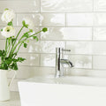 Chrome-finished single-handle bathroom faucet with sleek modern design featured with china white large brick tile background