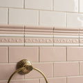 Gold-toned brass towel ring with fluted circular design mounted on pink tiled wall in Clare Half Tile setting