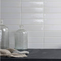 Clear glass bottle with vertical ridges and rounded neck shown with cliff brick tile background