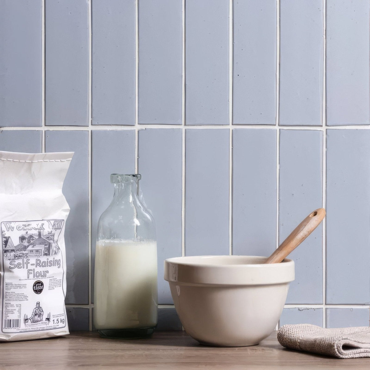 Cream-colored ceramic mixing bowl with wooden spoon resting inside for cloud smooth brick tile kitchen use