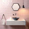 Black ceramic bowl sink with matte finish on white marble countertop in clover field tile setting