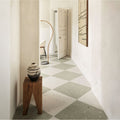 A ceramic vase with black base and white swirling patterns displayed on a rustic wooden pedestal alongside confetti cream terrazzo effect tile