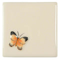 Cream-colored ceramic coaster with hand-painted copper butterfly featuring orange wings and black-tipped edges
