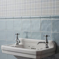 White ceramic pedestal sink with chrome cross-handle faucets featuring cornflower torus moulding design