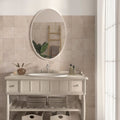 Oval-shaped mirror with sleek white frame mounted above sink featuring cotto blanc terracotta effect tiles background