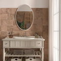 Oval-shaped mirror with white frame mounted above bathroom vanity with cotto natural terracotta effect tiles