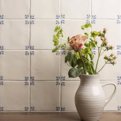 Cream-colored ceramic pitcher with ribbed texture and handle holding pink roses and greenery in country delft cornelia style