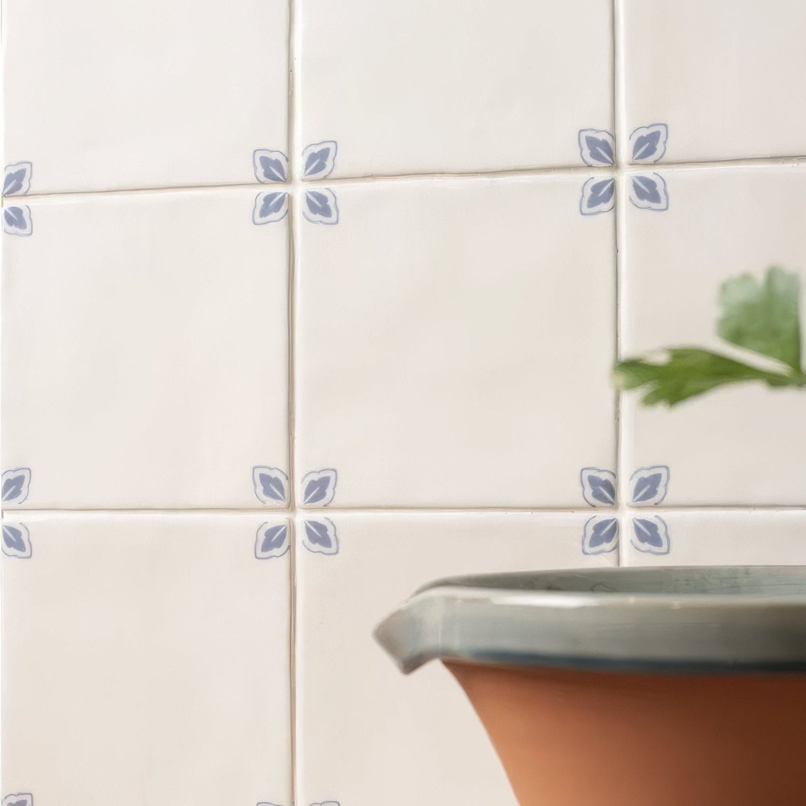 Off-white ceramic tiles with subtle blue leaf motifs in a grid pattern from country delft dorothea collection