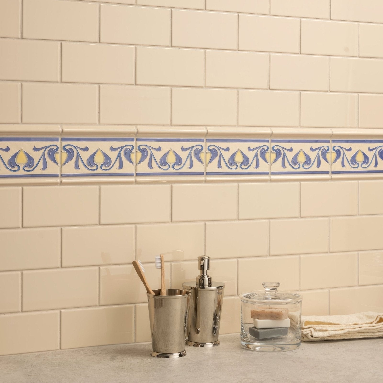 Cream-colored subway tile wall with decorative blue and yellow patterned border tile in county white albert moulding