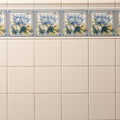 Beige ceramic county white field wall tile with decorative blue and yellow floral border motifs