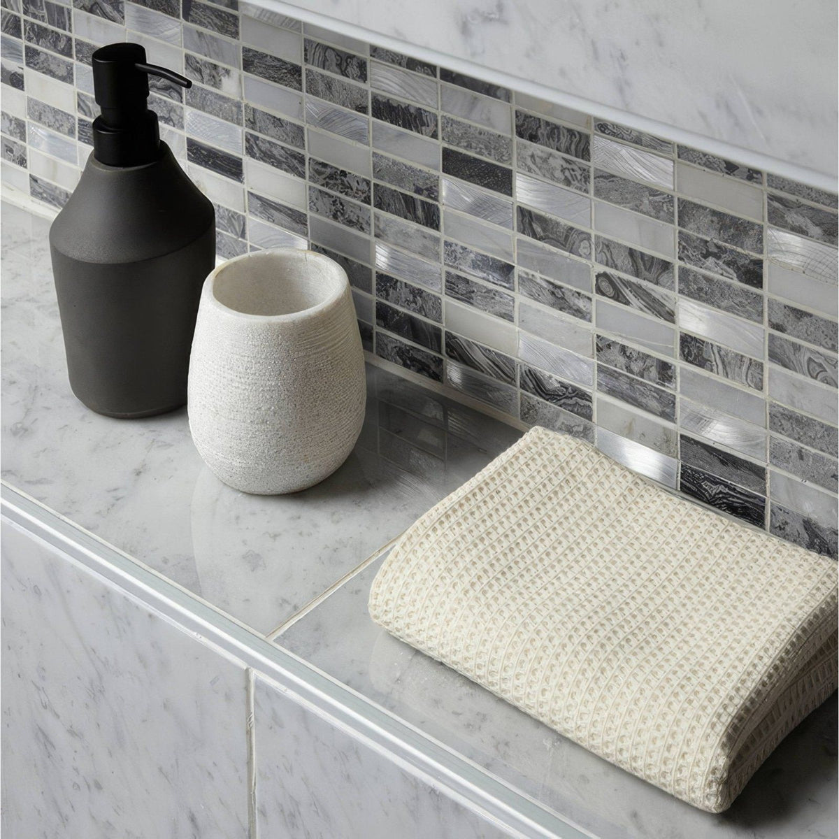 Creswell Grey Stone & Metal Mix Linear Mosaic grey stone and metal mosaic with a cream waffle towel on a marble countertop