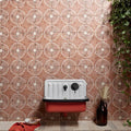 A vintage-style cuba porcelain vedado cotto enamel sink in white and red with black fixtures against a patterned wall