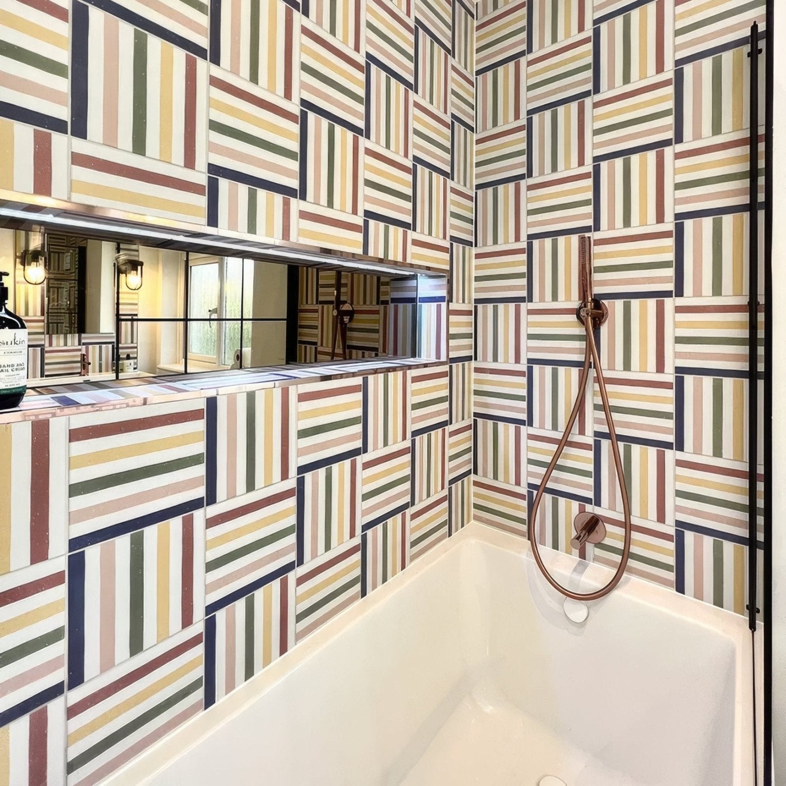 The bathroom features a white porcelain deck chair bathtub with rose gold fixtures and striped multicolored tiles