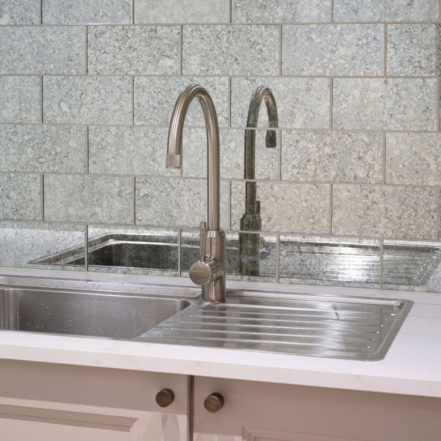 Modern brushed stainless steel kitchen faucet with sleek curved spout and rounded handle for deco glass pewter wall tile setup