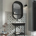 Black oval mirror with integrated shelf above white sink and black vanity base featuring decorata 09 patterned tile