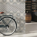 Decorata 10 patterned 15 x 15cm tile with dark green bicycle design featuring brown leather saddle and silver spokes