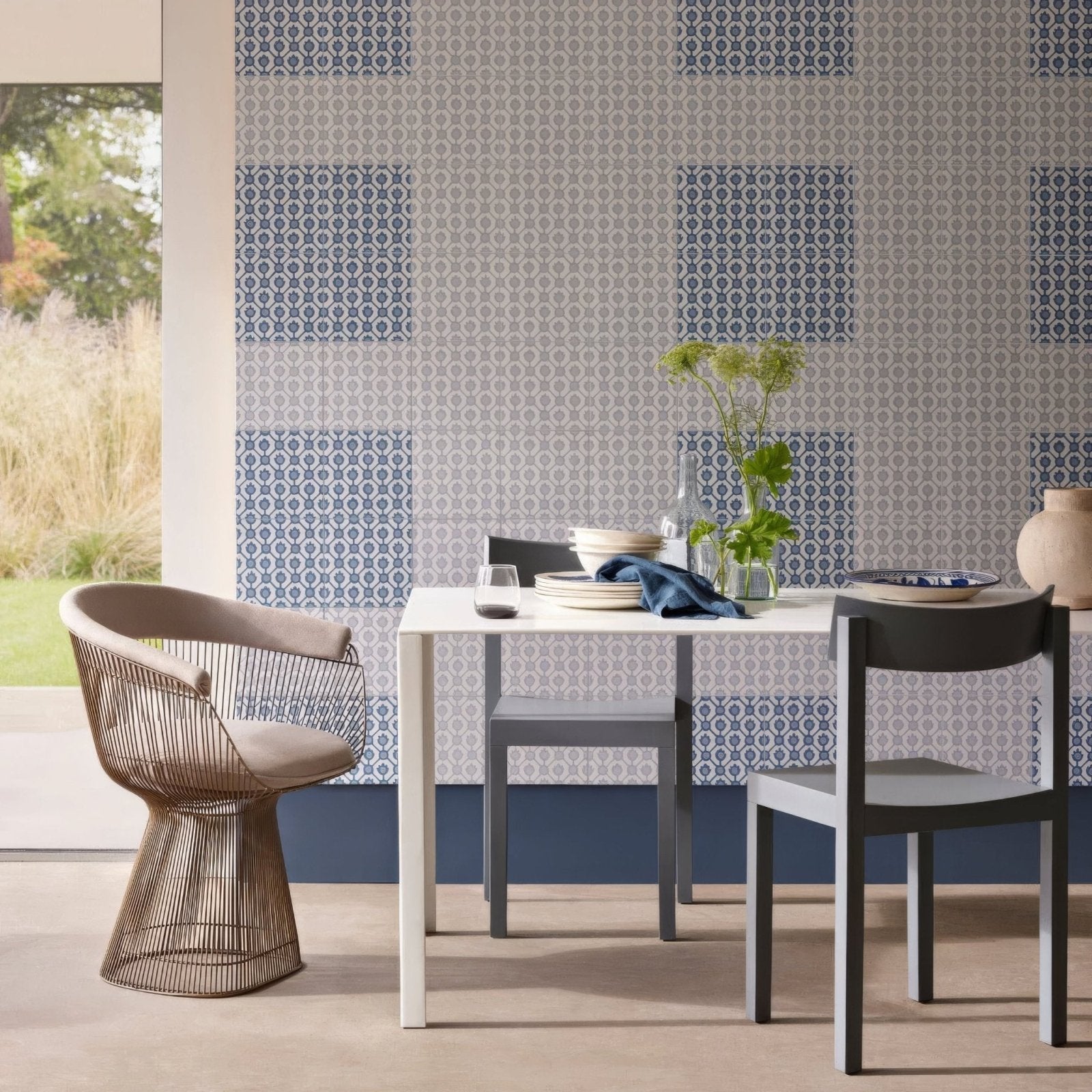 A modern Designers Guild Jaal Cobalt wireframe chair with beige cushion and bronze-toned metal frame