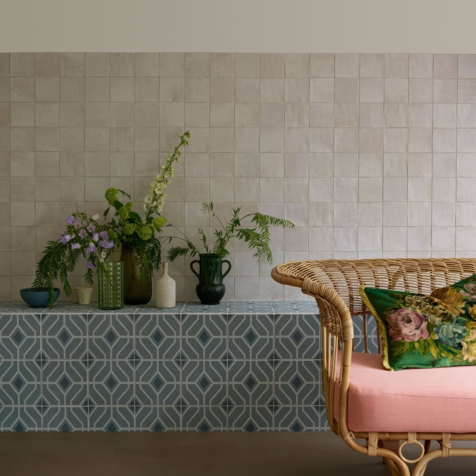 Woven rattan bench with pink cushion and green floral pillow in designers guild laterza slate blue upholstery
