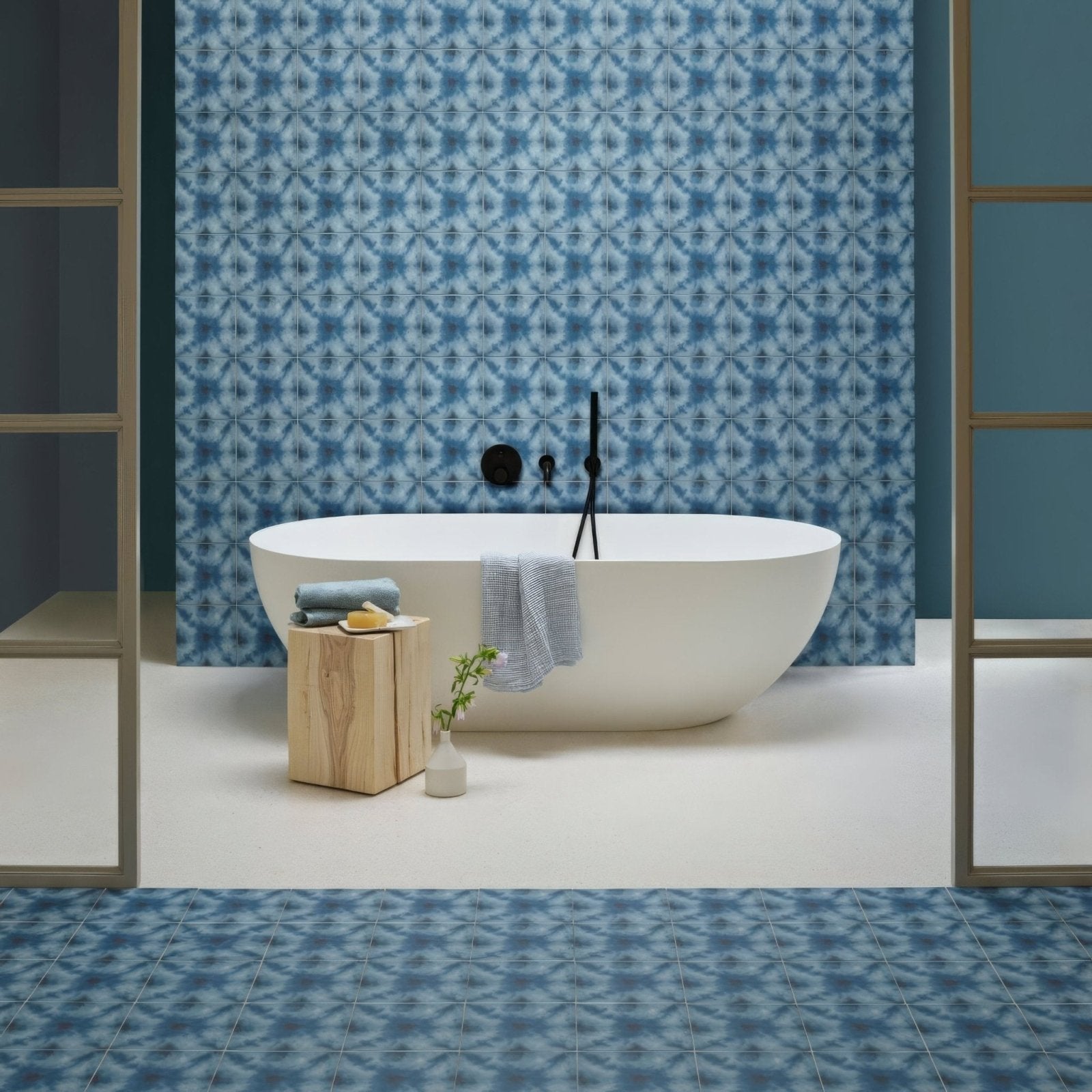 White freestanding bathtub with sleek modern design and black faucet fixtures in designers guild shibori cobalt style