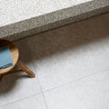 A light blue dijon natural 90 x 60cm cloth folded neatly on a round wooden stool