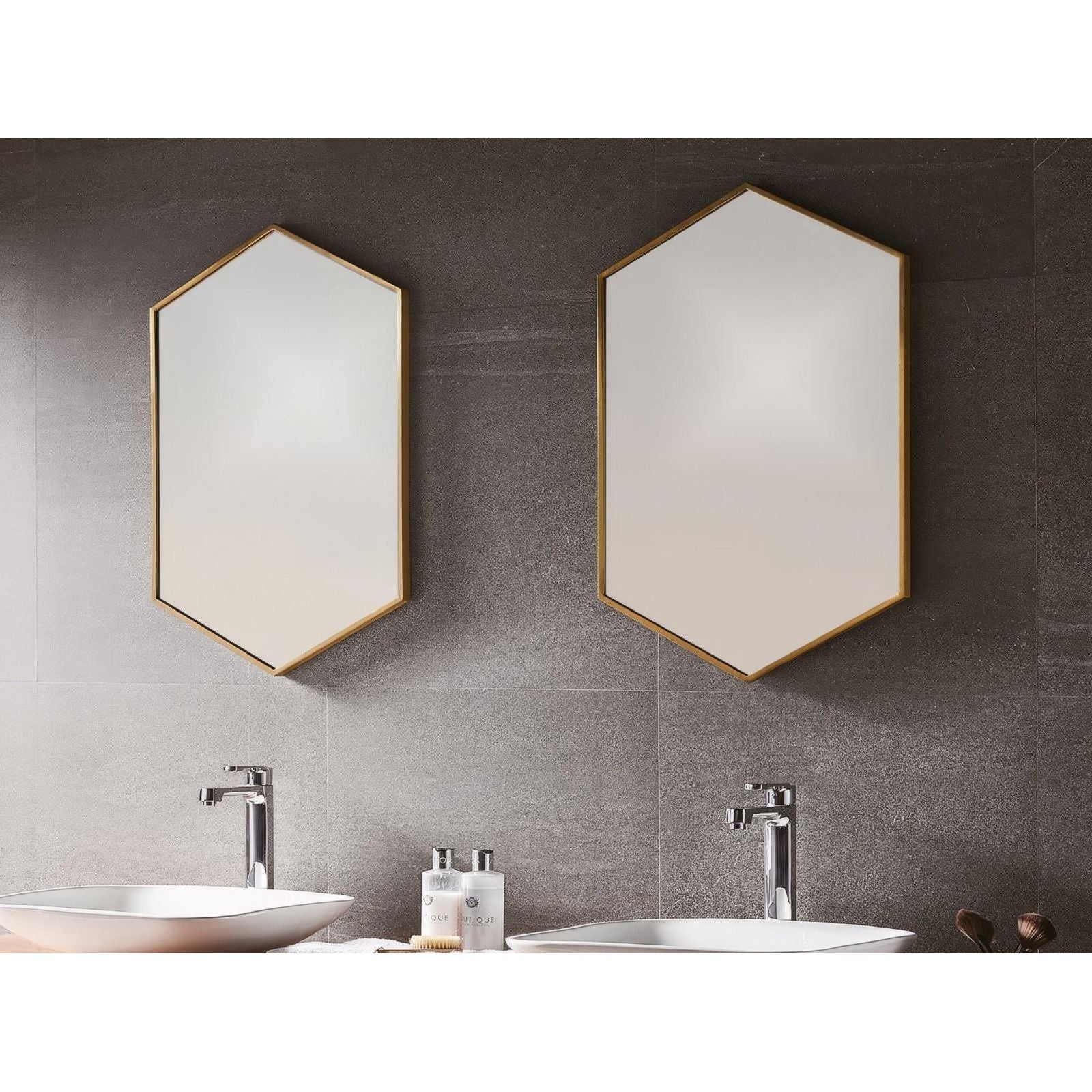 Two docklands hexagonal mirrors with gold-toned brushed brass frames on a dark gray tiled wall