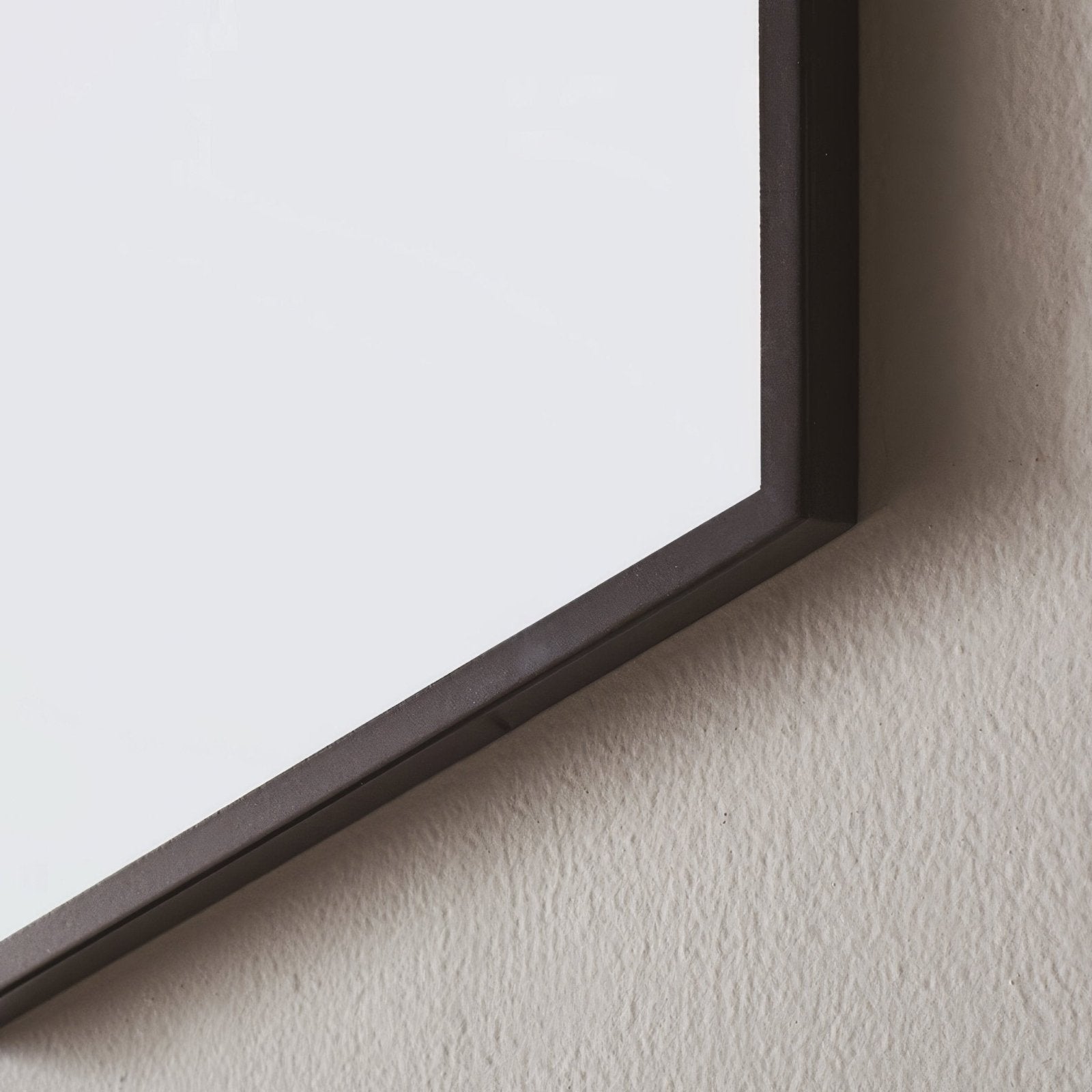 A sleek dark gray docklands rectangular mirror 120x70cm with a minimalist frame mounted on a textured wall