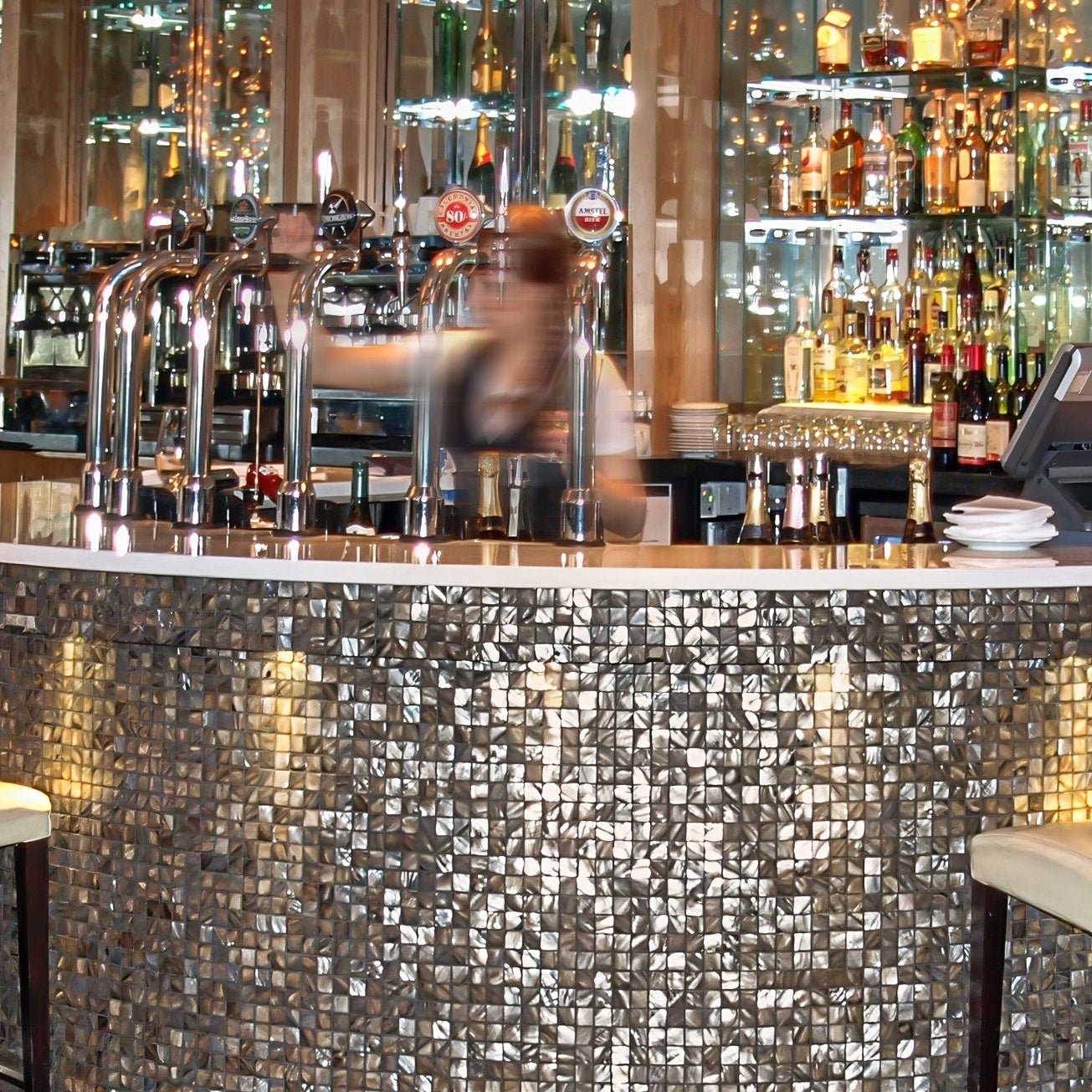 The bar counter features dove grey 25mm square silver-toned reflective mosaic tiles for a shimmering effect