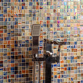 Dream Film Faced Mosaic 25mm iridescent glass mosaic in a shower with a chrome showerhead and tap