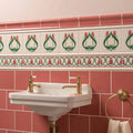 White ceramic sink with gold toned faucets and matching pedestal base paired with duchy pink field tile wall