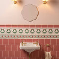 White ceramic pedestal sink with gold-toned faucets installed above duchy pink field tile bathroom wall
