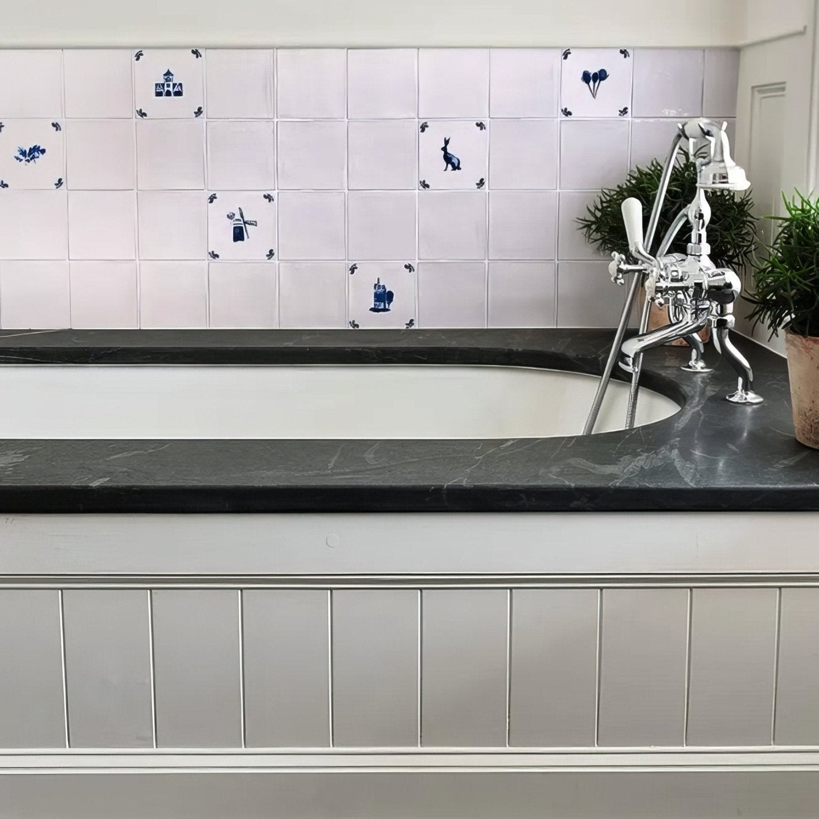 White bathtub with sleek black marble surround and chrome faucet installed with dyrham dairy ceramic chalk white field tile
