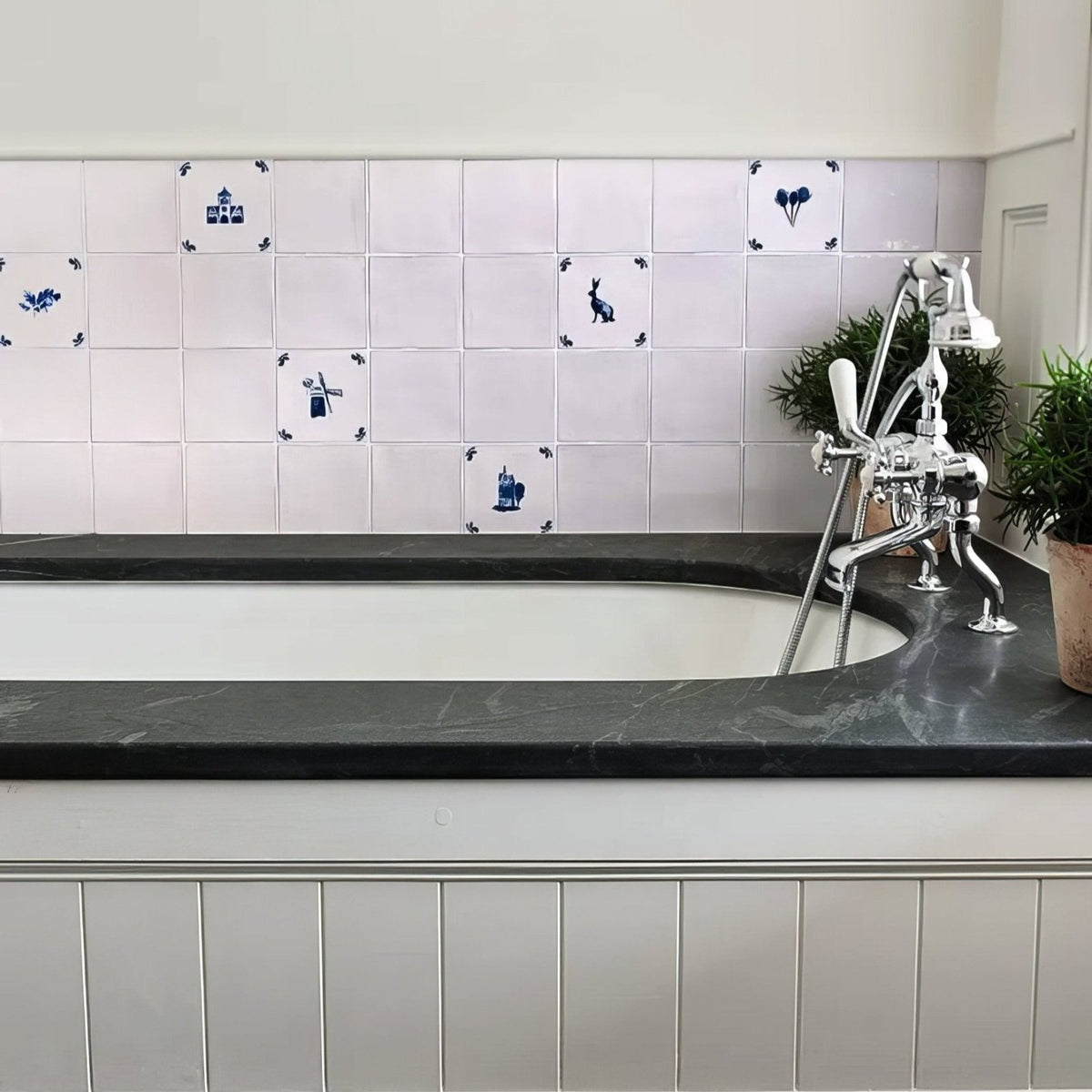 White bathtub with sleek black marble surround and chrome faucet from dyrham dairy ceramic decors collection