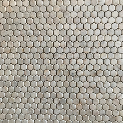 Close view of tumbled Calacatta Sugar hexagons showing worn rounded edges and a lightly pitted matt face
