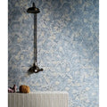 A dark bronze vintage-style earthenware porcelain linen showerhead with ornate handle mounted on blue hex tiles