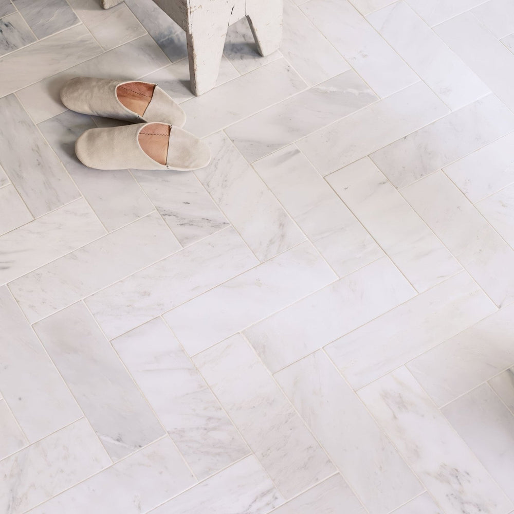 Pair of slippers on a marble floor in East Hampton Marble Tile 10x30cm with a herringbone pattern