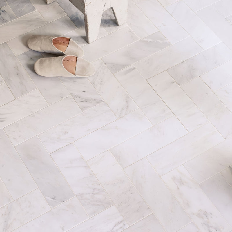 Pair of slippers on a marble floor in East Hampton Marble Tile 10x30cm with a herringbone pattern