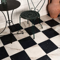East Village Porcelain Bianco 60 x 60cm white marble-effect porcelain flooring with a dark green metal chair