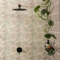 Black matte-finish showerhead with circular textured surface mounted on eden hothouse tropical leaf tiled wall