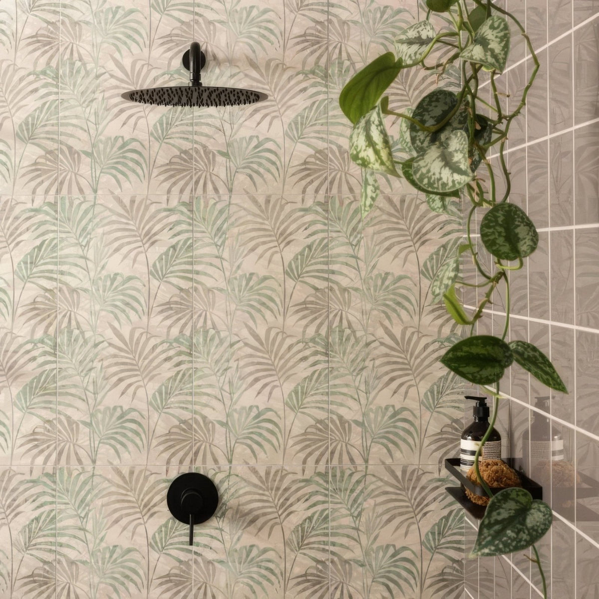 Black matte-finish showerhead with circular textured surface mounted on eden hothouse tropical leaf tiled wall