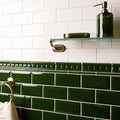 Edwardian green dentil moulding featuring deep green glossy rectangular subway tiles with decorative border and white grout