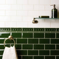 Edwardian green omega moulding featuring deep green glossy rectangular subway tiles with white grout and decorative border