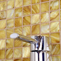 Emerald Gold 25mm Square golden mother-of-pearl mosaic behind a chrome tap with a white handle