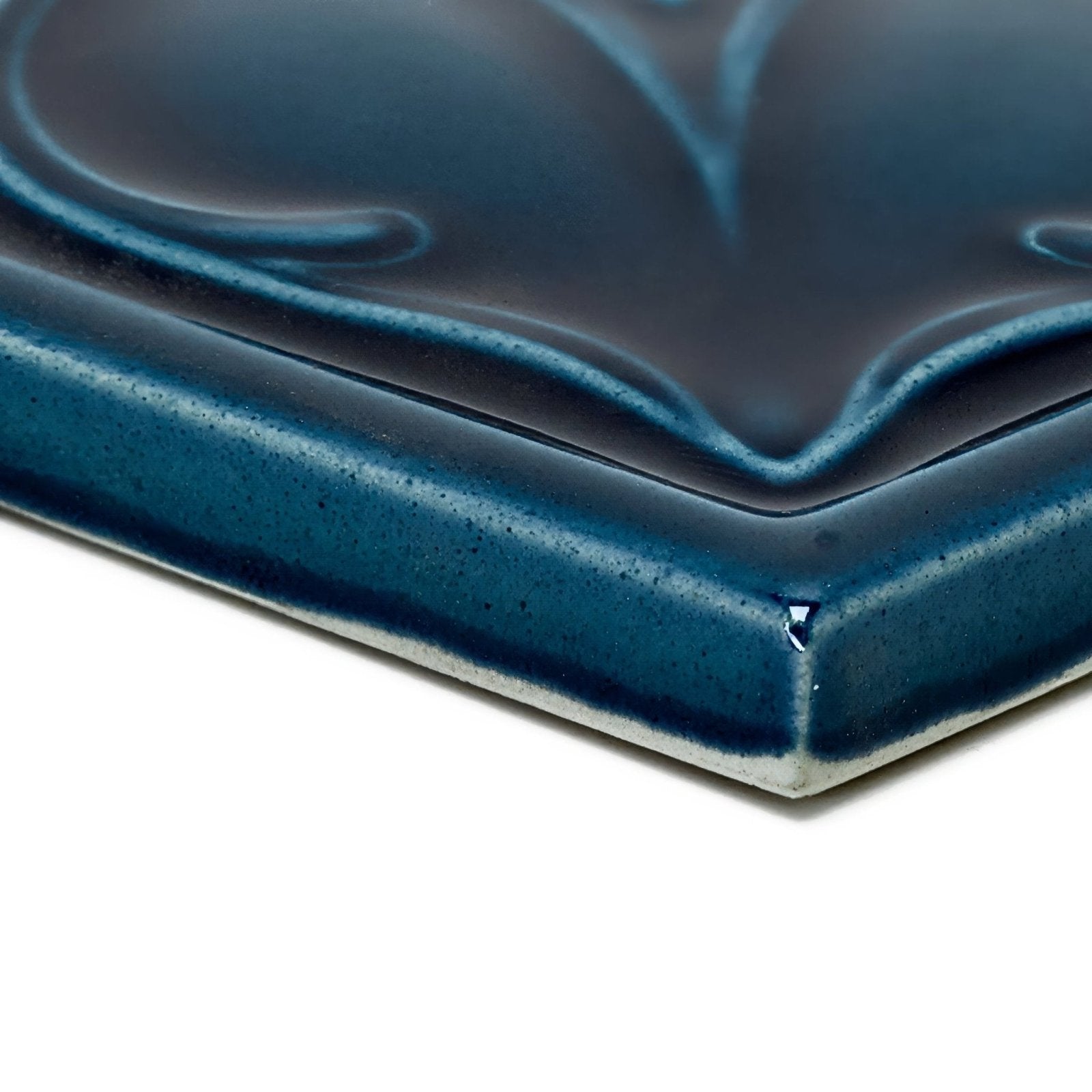 A glossy deep blue Empress Beatrice Tourmaline ceramic tile with raised leaf pattern and speckled glaze