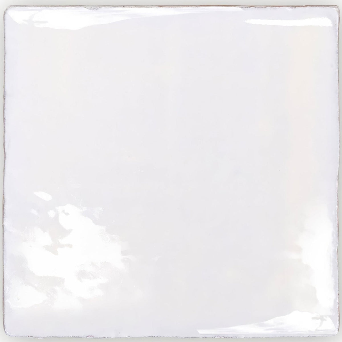 A square glossy white ceramic tile with slightly uneven edges and subtle reflections from traditional english delft base